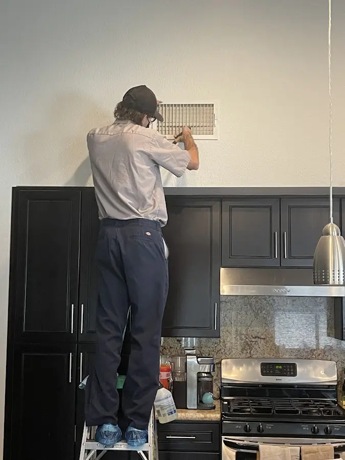 Technician inspecting an air vent during HVAC service in Dakota Dunes